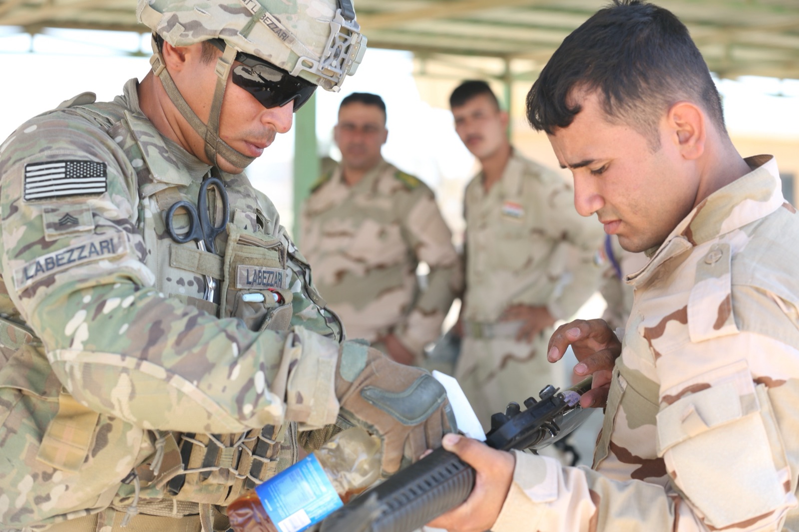 Un paracaidista estadounidense ayuda a un soldado iraquí con su fusil durante un entrenamiento en Camp Taji, Irak, en 2015.