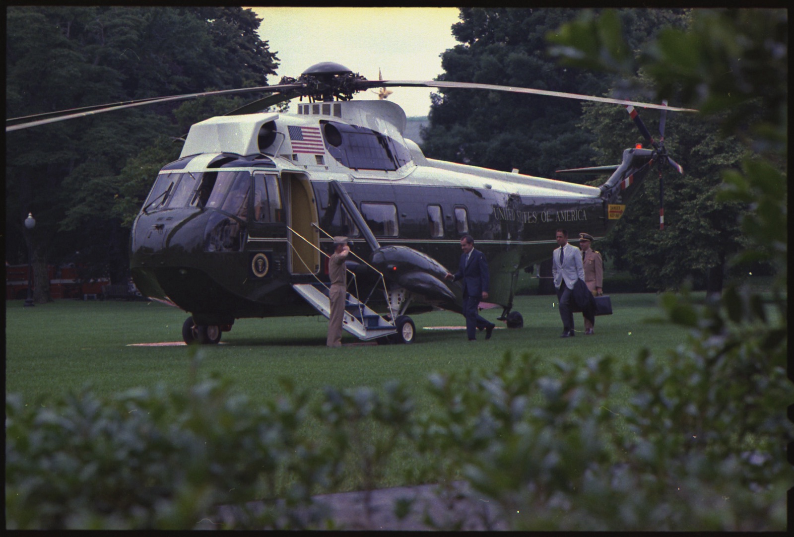 El presidente Richard Nixon camina hacia el helicóptero Marine One el 16 de julio de 1972; detrás, a la derecha, un ayudante militar de uniforme lleva un maletín.